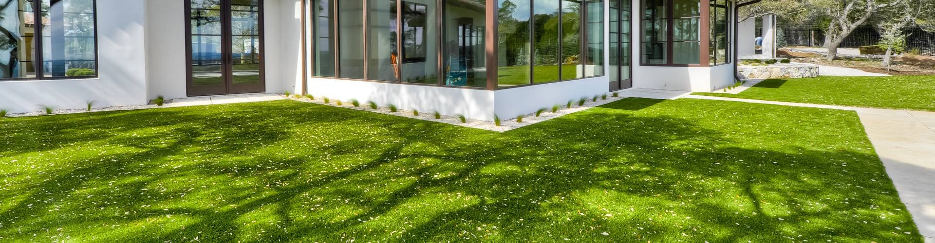 Southwest Greens lawn turf grass surrounding a modern luxury home with floor-to-ceiling windows and pristine landscaping